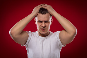 Handsome Man Holding His Head On Red Background